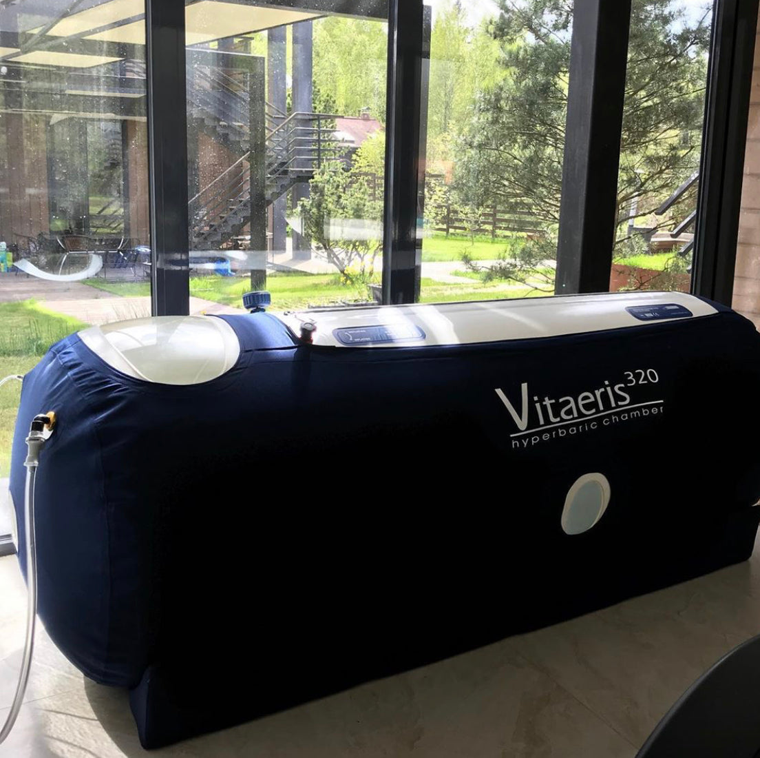 Vitaeris hyperbaric chamber in a room with large windows showing an outdoor view.