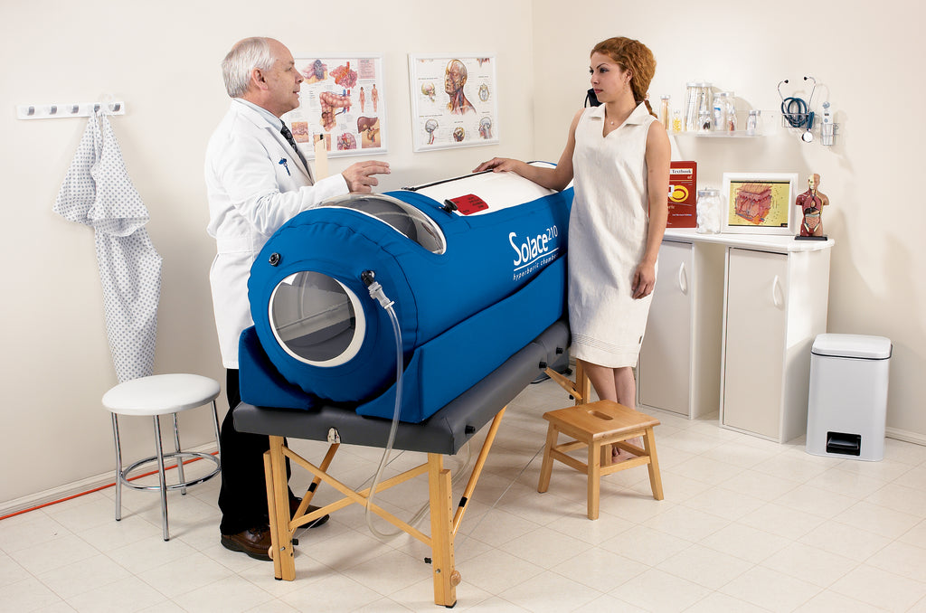Person using a blue hyperbaric chamber with a doctor in a clinical setting.