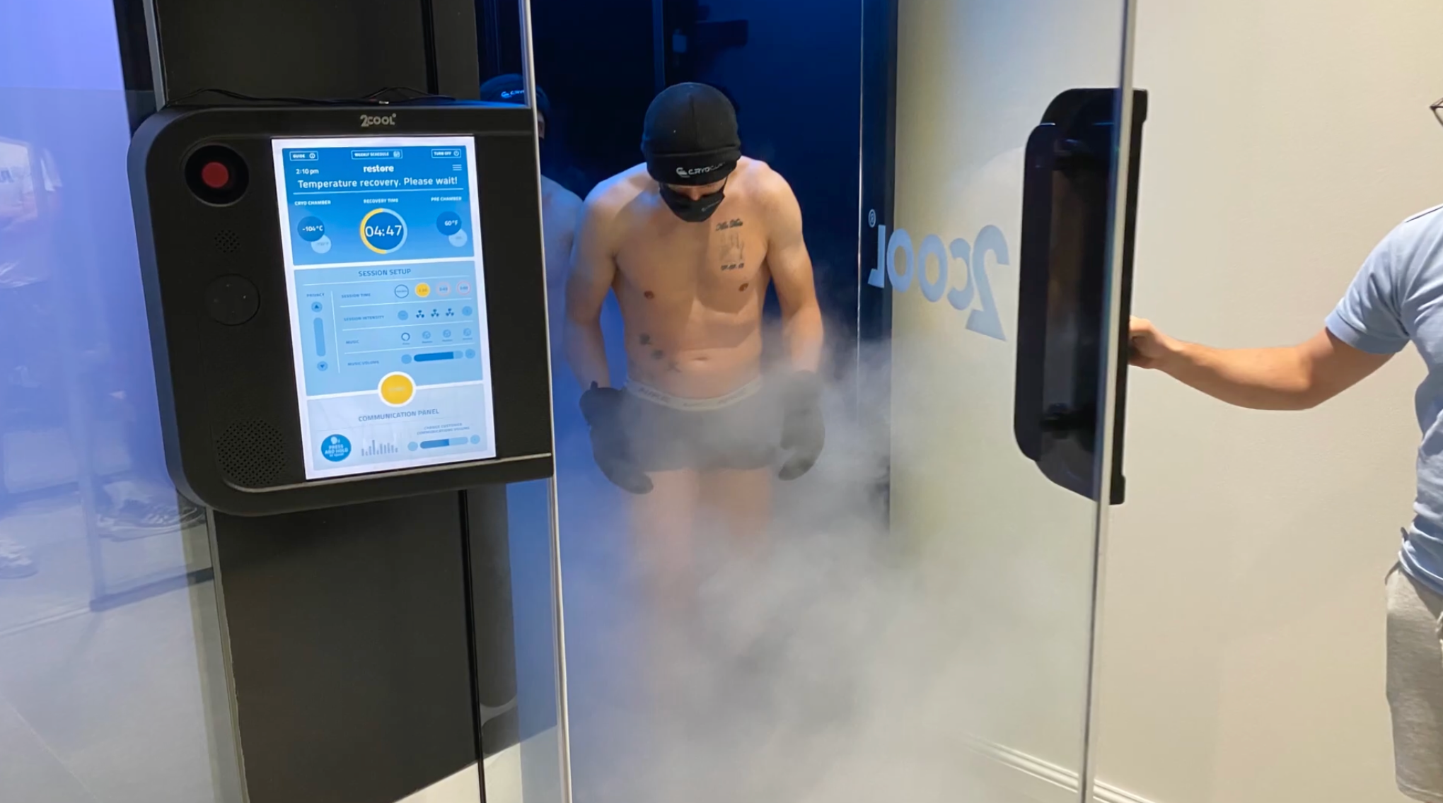 Person entering a cryotherapy chamber with a digital display on the door.